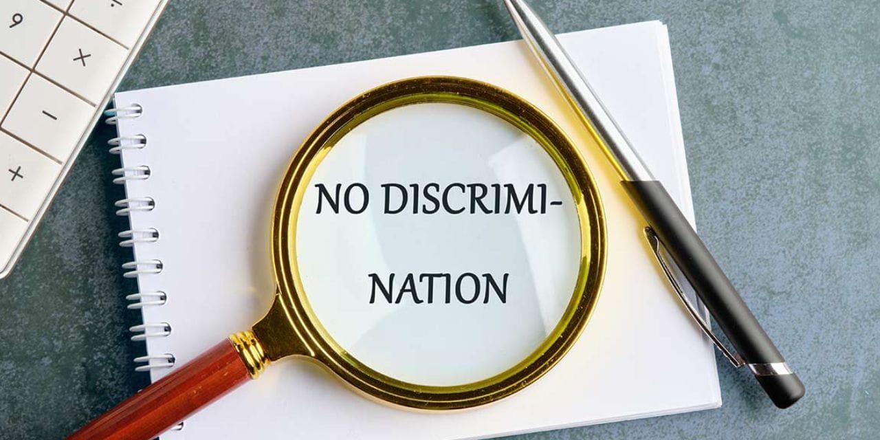 A magnifying glass over the paper with 'No Discrimination' written on it