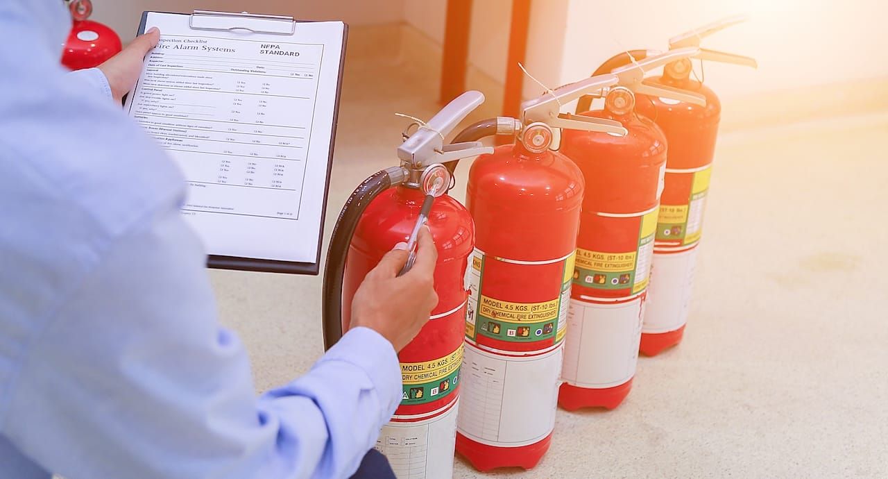 man checking fire extinguishers; restaurant kitchen fire safety measures