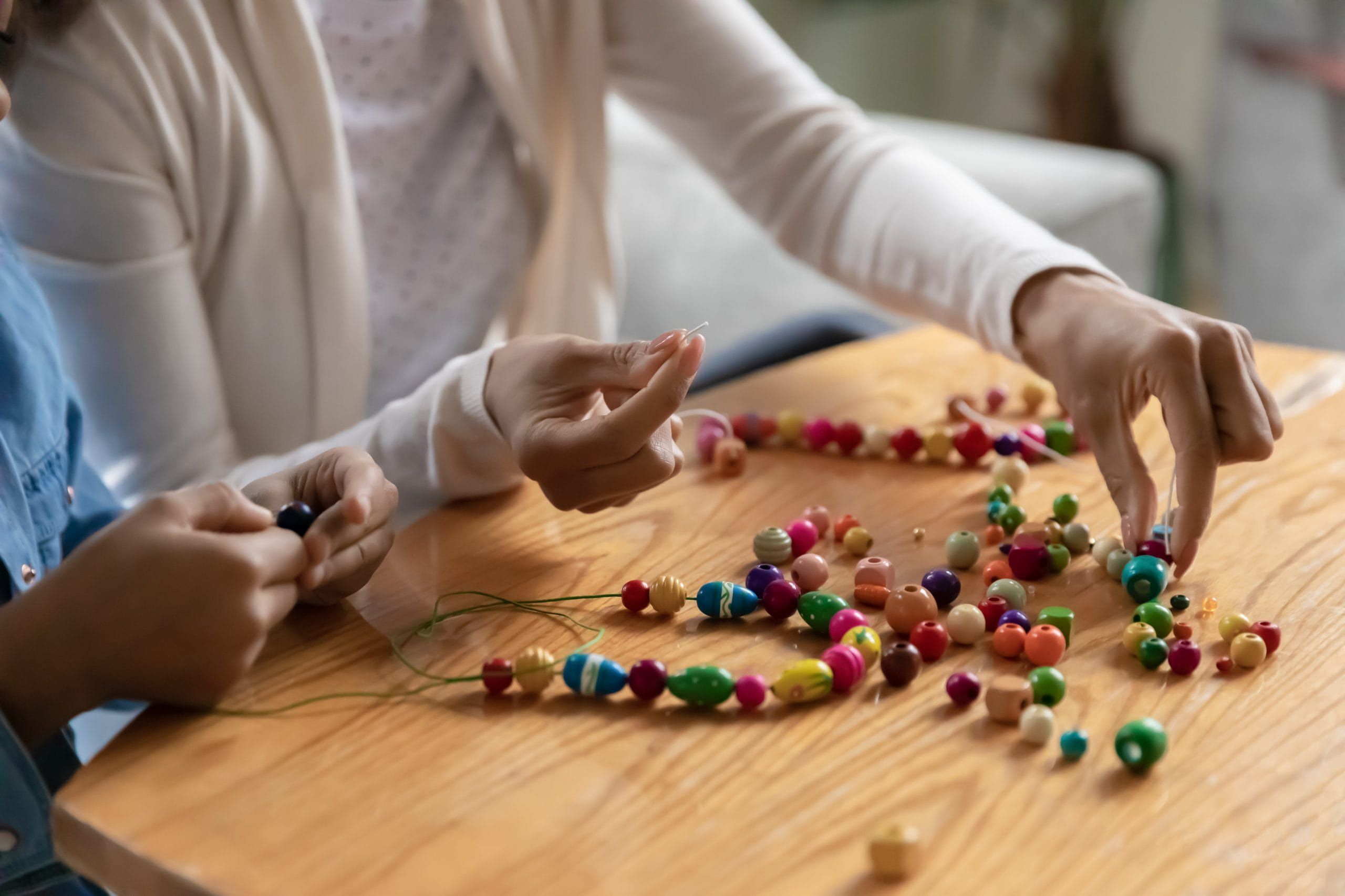 mom and child using beads to make a necklace