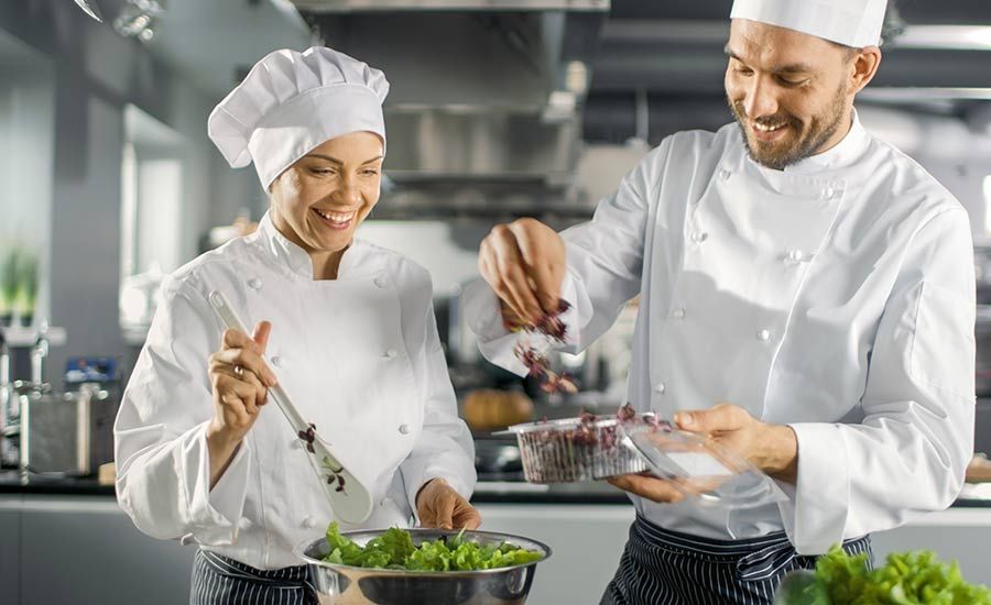 One female cook and one male cook preparing ingredients